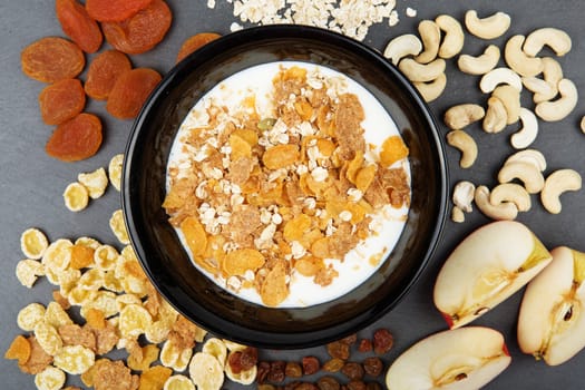 Muesli, nuts, fruits, milk and oatmeal for breakfast. Plate of oat flakes, cashew, apples and seeds for tasty breakfast on dark slate tray. Diet, Detox, Clean Eating or Vegetarian concept.