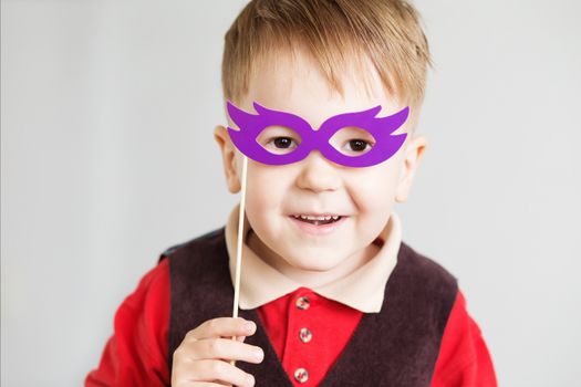 Portrait of a happy little kid with funny paper glasses against a white background
