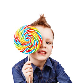 A boy in a denim shirt eating lollipop. Happy kid with a big candy isolated on white background