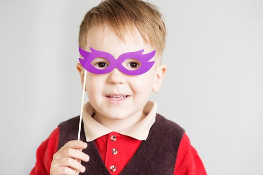 Portrait of a happy little kid with funny paper glasses against a white background