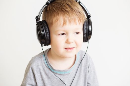 Adorable little baby boy in headphones enjoy with a music