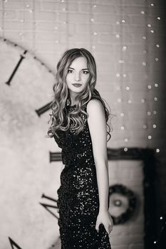 Portrait of a beautiful long-haired young girl in black Evening Dress in interior with Christmas decorations. Black and white photography