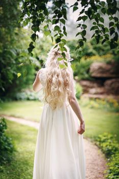 Bride with long fair hair from back in the garden