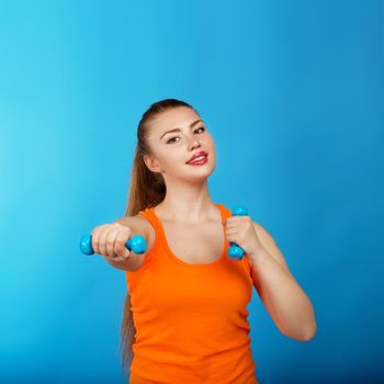 Portrait of a beautiful young athletic girl with dumbbells