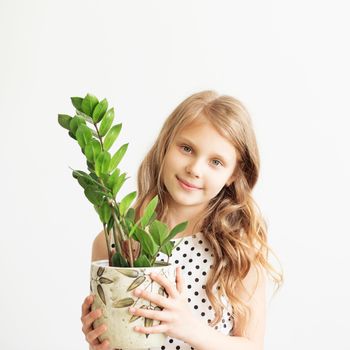 Portrait of a lovely little girl with green houseplant against a white background