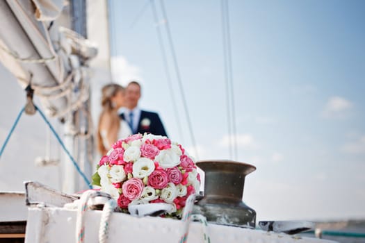 Wedding bridal bouquet with pink and white roses on a yacht against the background of the bride and groom. Wedding concept