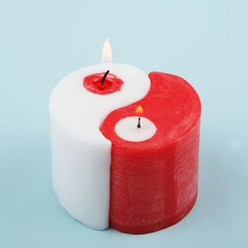 White and red Yin Yang handmade candle on blue background. Double candle. Two candles in one