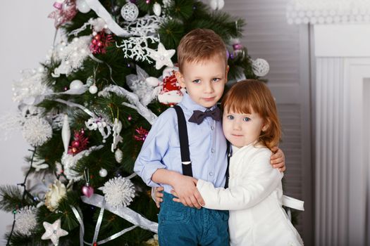 Portrait of a happy children - boy and girl. Little kids in Christmas decorations. Brother and sister hugging.