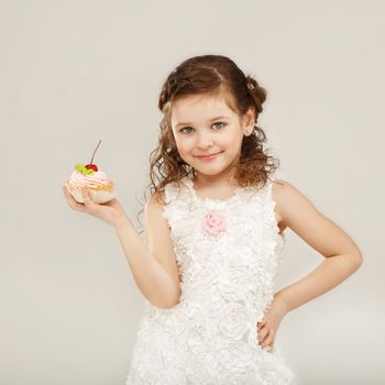 Beautiful little girl holding a delicious appetizing cake with cherry