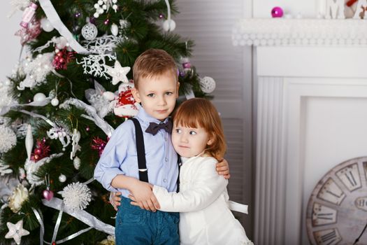 Portrait of a happy children - boy and girl. Little kids in Christmas decorations. Brother and sister hugging.