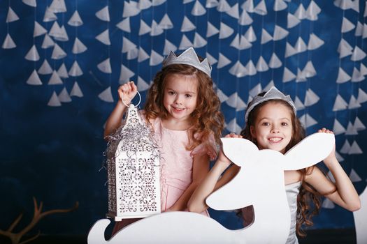 Little girls in christmas decorations. Portrait of Beautiful little girls with long curly hair with crown. Decor winter forest. Little Princess