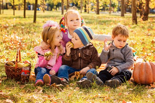 Four happy children playing in autumn park with fruits