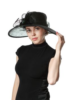 Portrait of a beautiful woman in a black dress and hat standing and holding a hat isolated on white background