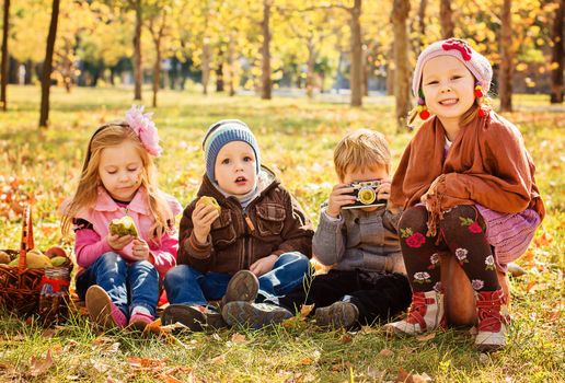 Four happy children playing in autumn park with fruits