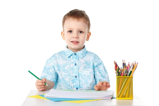 Smiling little boy draws with crayons isolated on white background