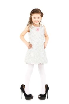 Little girl dressed big mother's shoes isolated on white background