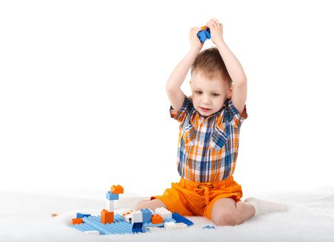 Little cute boy playing with designer on the floor isolated on white background