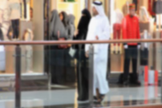 Arab sheikhs men and their wives and families in a mall make a purchase, Dubai, people go to the mall, market, blurred for background