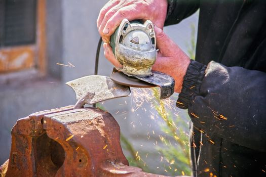 sharpening garden tools hoe using grinder close-up, Machine for grinding / welding metal and sparks spread