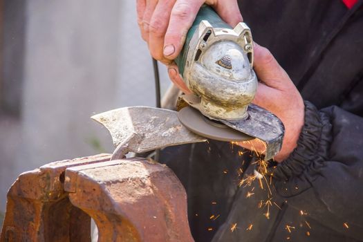 sharpening garden tools hoe using grinder close-up, Machine for grinding / welding metal and sparks spread, Soft focus