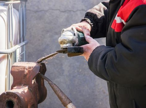 sharpening garden tools hoe using grinder close-up, Machine for grinding / welding metal and sparks spread, Soft focus