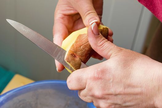 close-up of hands peeling potatoes, cleaning raw fresh potatoes, cooking in the kitchen