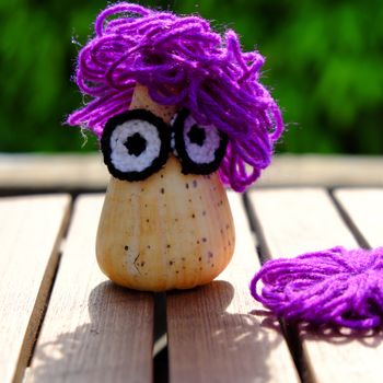 Funny creative from hobby, owl make from conch shell with knitted eyes, violet wool hair on green background, amazing diy ornament with enjoyment life