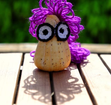 Funny creative from hobby, owl make from conch shell with knitted eyes, violet wool hair on green background, amazing diy ornament with enjoyment life