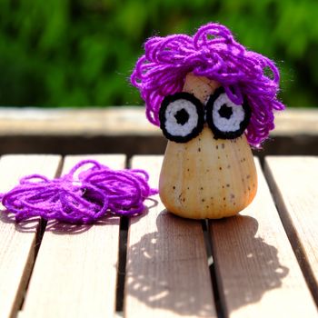 Funny creative from hobby, owl make from conch shell with knitted eyes, violet wool hair on green background, amazing diy ornament with enjoyment life