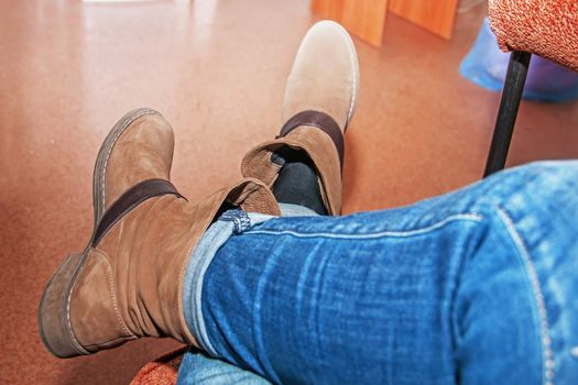 female legs in brown boots, women's shoes, sitting on the couch,out of focus