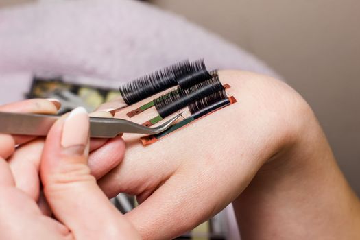 artificial eyelash extensions, the master's hand, eyelash extension procedure in a beauty salon, the beauty industry is gushing into the hands of the masters