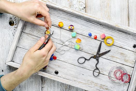 Women hands at work on making jewelry from beads