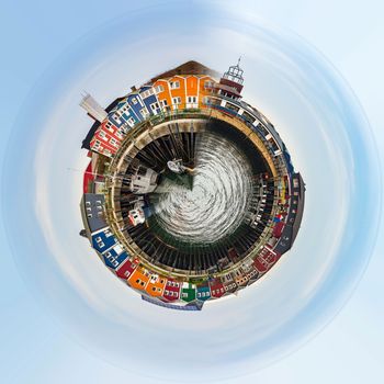 Planet of panorama of colored Crab fisher hutches at harbor Island Helgoland, Germany, nordic style houses with boat and blue sky. Little planet concept. Tiny planet projection 