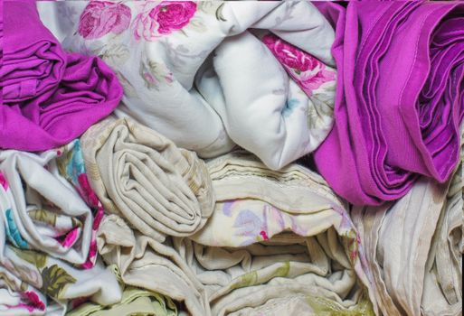 bedding rolls piled stacks in a closet, cabinet furniture for home and home textile interior, colorful, sheets and towels, fabric rolls, for backgrounds and textures