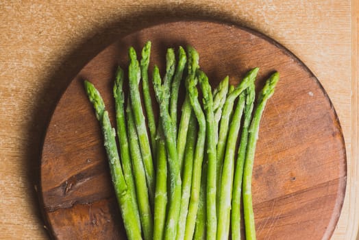 Frozen sticks of asparagus on rustic wood background. horizontal view