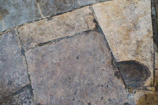 Rough stone tile floor with cracks and small stones abstract background texture.