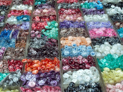 Various colorful buttons in plastic box for sell, focus on the center of image.