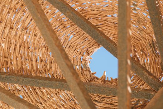 Wicker metal vintage umbrella on a background of blue sky, fragment.