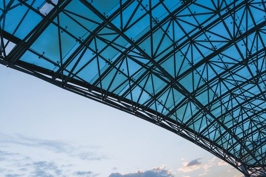 Bottom view of modern glass roof in business district in evening light at sunset with copyspace.