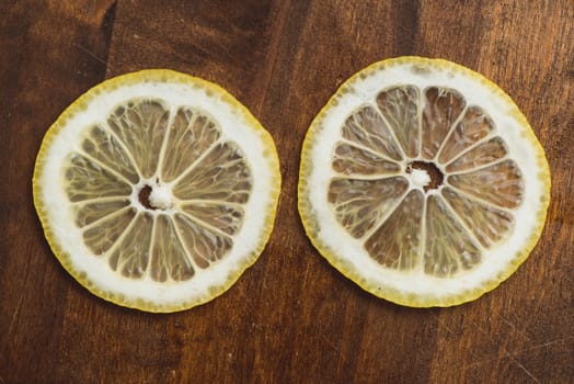 two thin slices Fresh Lemon on Wood Table Background, Rustic Style