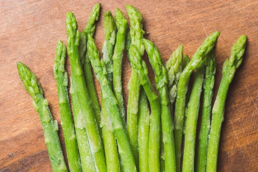 Frozen sticks of asparagus on rustic wood background. horizontal view