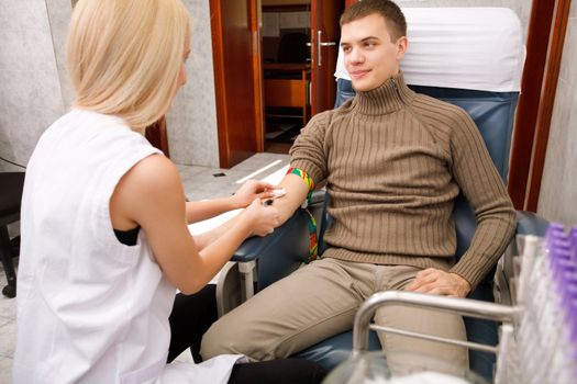 Young nurse draws blood from a man's arm