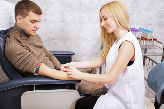 Young nurse doing procedure of a blood capture from a vein 