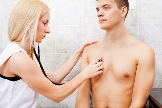 Young female doctor examining young man with stethoscope