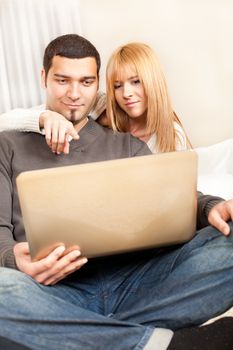 Happy young couple sitting at living room, and browsing internet