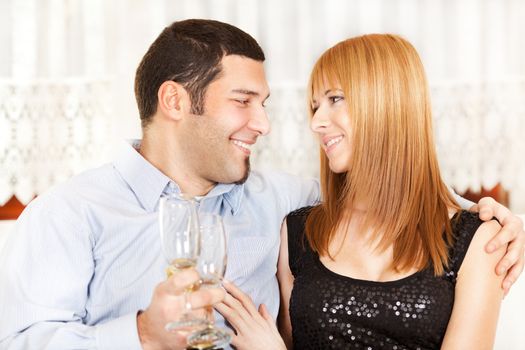 Happy young couple toasting their anniversary with champagne at home ambient