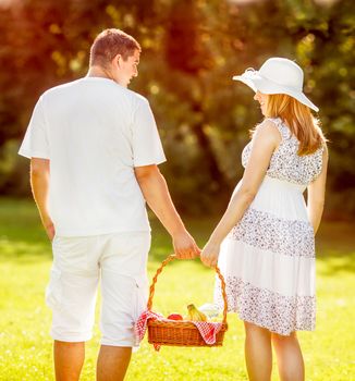 Couple holding a picnic basket and going to picnic