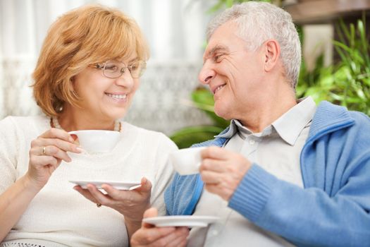 Happy senior couple drinking coffee at home