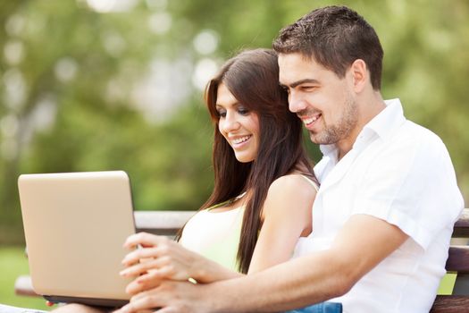 Happy couple using laptop in the nature