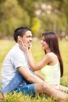 Happy young man and beautiful girl sitting in the park